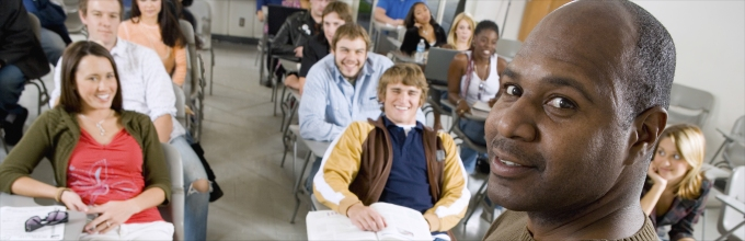 An instructor in front of a classroom of smiling students