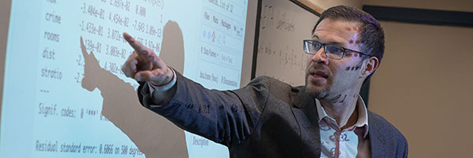 Instructor pointing out notes on a white board.