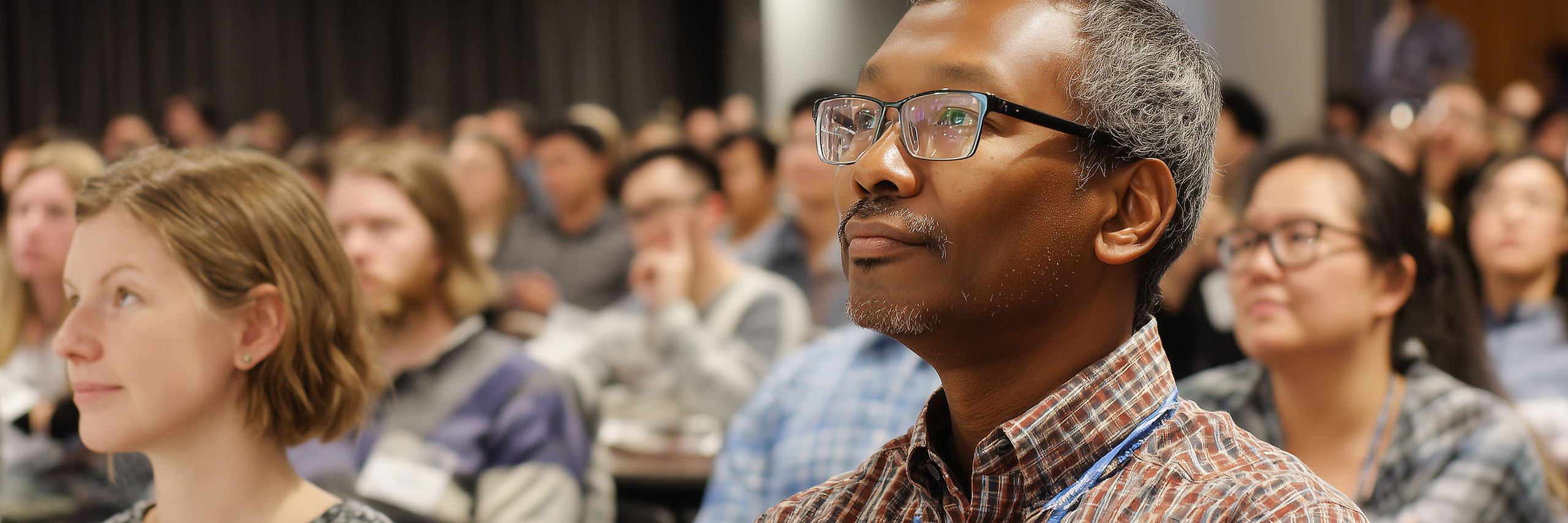 Professors and Staff in a classroom, attentively listening.